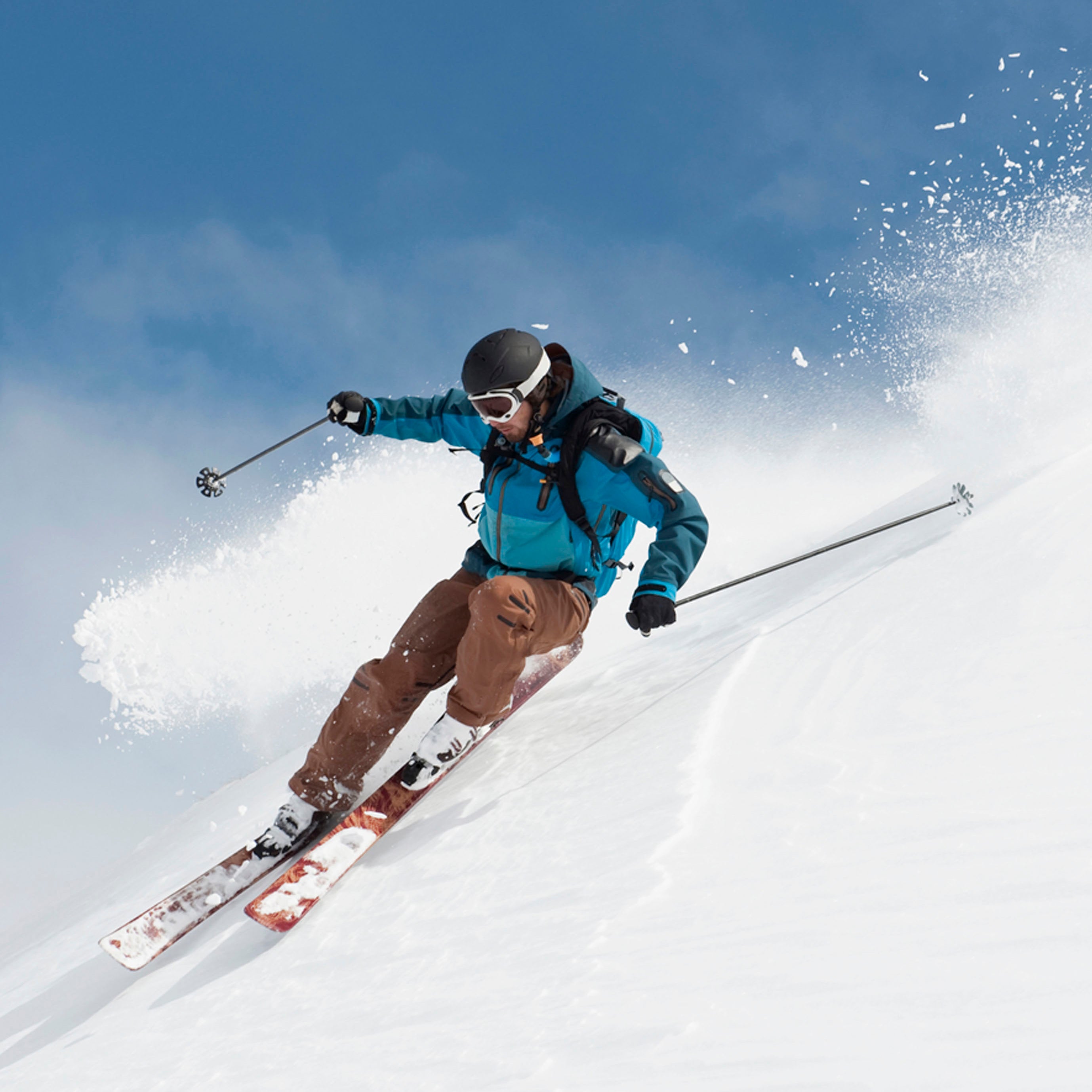 Skier in action on a snowy slope with a clear blue sky.