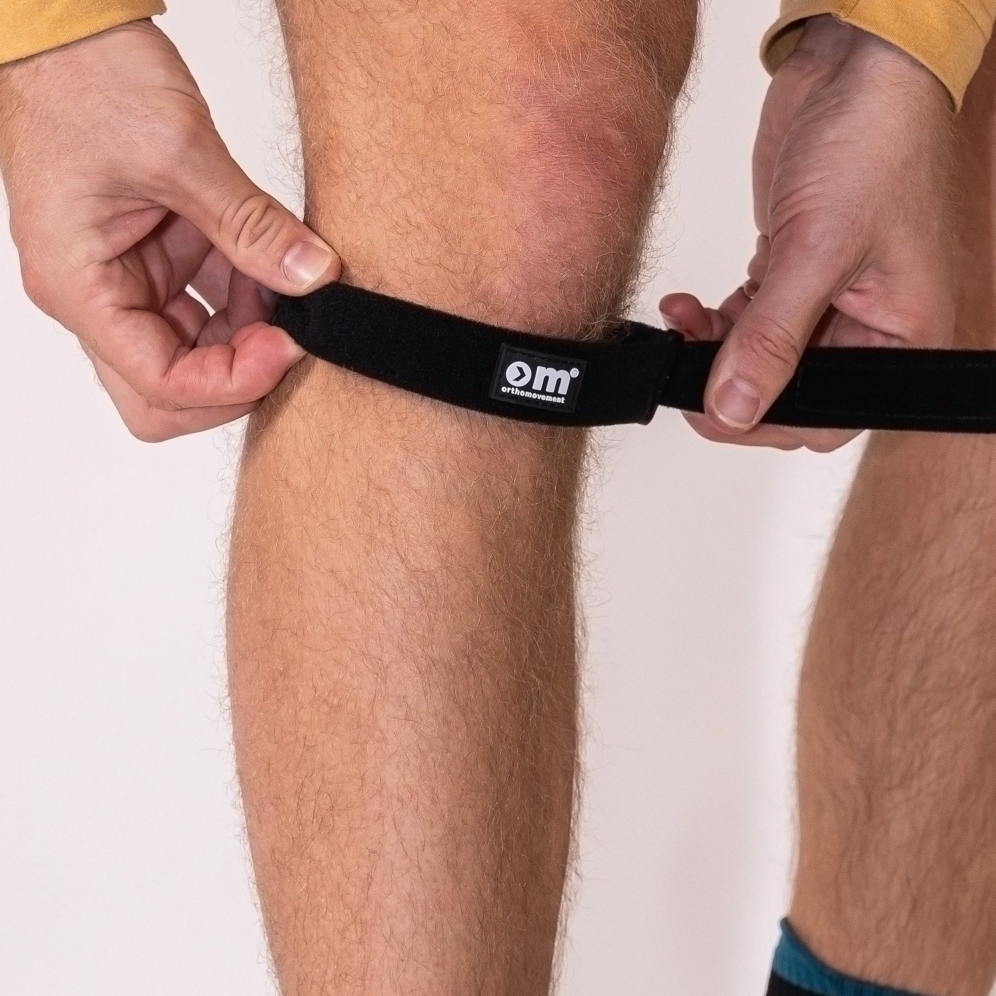 Person wearing a knee strap, black socks and black athletic shoes with a white background